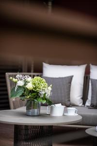 a vase of flowers on a table with a couch at Relais et Châteaux Le Chambard in Kaysersberg
