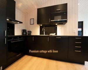 a kitchen with black cabinets and a microwave at Geirangerfjorden Feriesenter in Geiranger