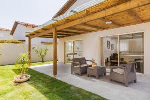 a patio with chairs and a wooden pergola at Tal Shahar Zimmers in Tal Shaẖar