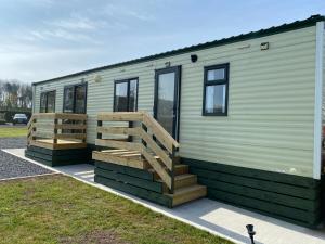a green trailer with a ramp and a house at Charming two bedroom static caravan in whithorn in Newton Stewart