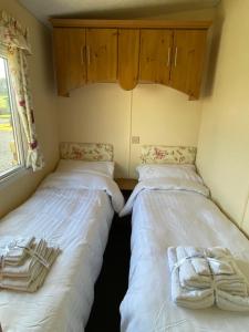 two beds in a small room with wooden cabinets at Charming two bedroom static caravan in whithorn in Newton Stewart