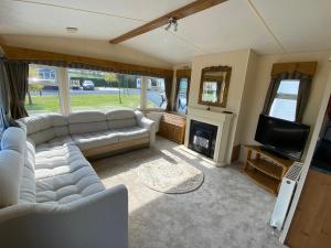 a living room with a couch and a television at Charming two bedroom static caravan in whithorn in Newton Stewart