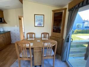 a kitchen with a wooden table and chairs at Charming two bedroom static caravan in whithorn in Newton Stewart