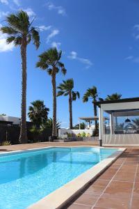 a swimming pool with palm trees in the background at Casa Amelia in Yaiza