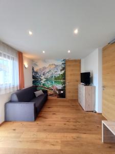 里斯孔內的住宿－Alpine Deluxe 2.0，客厅配有沙发和墙上的绘画