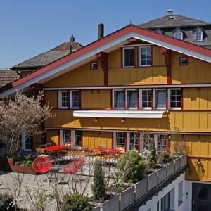 un gran edificio amarillo con mesas y sillas delante de él en Alte Metzg - Boutique Pension en Appenzell