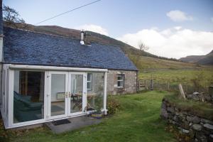 una casa con una gran puerta corredera de cristal en Inverlael Farm Cottages en Inverlael