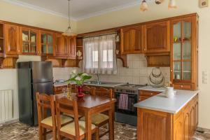 a kitchen with wooden cabinets and a table and a refrigerator at Spiti Anna Maria in Corfu +21 photos