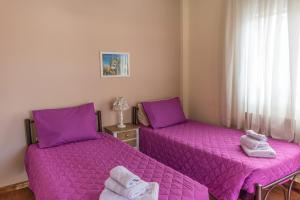 two beds in a room with purple sheets at Spiti Anna Maria in Corfu