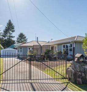 a metal gate in front of a house at Cosy family home with a sunny deck in Rotorua