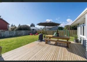 a wooden deck with a bench and an umbrella at Cosy family home with a sunny deck in Rotorua