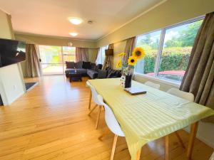 a living room with a table and chairs and a couch at Cosy family home with a sunny deck in Rotorua