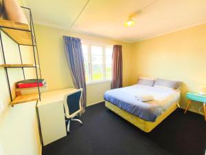 a bedroom with a bed and a desk and a ladder at Cosy family home with a sunny deck in Rotorua