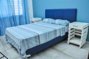 Dormitorio azul con cama y mesita de noche blanca en CASA Naranja.RR en Barrio San Isidro (2)
