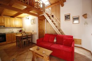 a living room with a red couch and a kitchen at Baita De Anna in Valdidentro