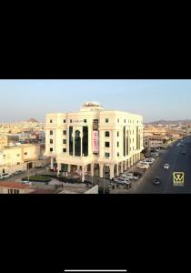 un grand bâtiment blanc avec une route devant lui dans l'établissement Al Wadaq Hotel, à Taif