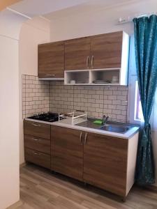 eine Küche mit Holzschränken, Spüle und Fenster in der Unterkunft Urcu Hotel in Antalya