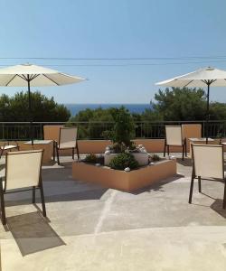 a patio with chairs and tables and umbrellas at Hermes in Agia Marina Aegina