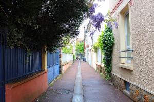 a narrow alley between two buildings with purple flowers at Apartments au Dream of horse, Dream of golf, Proche Hippodrome, Saint Cloud in Saint-Cloud