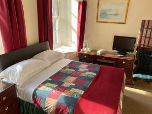 a bedroom with a bed and a desk and a tv at The Royal Crown Guest House in Aberdeen