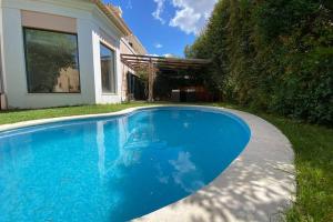 a blue swimming pool in front of a house at Cascais Guincho Beach Villa in Cascais