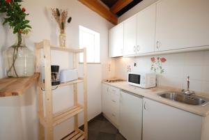 a kitchen with white cabinets and a sink at Quinta Rosa Branca in Tavira