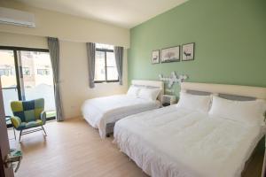 a hotel room with two beds and a chair at Summer Grass B&B 台東縣民宿1729號 in Taitung City
