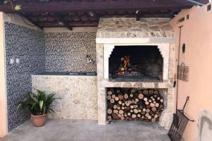 a stone fireplace with a fire in it at Orhideja Apartment in Lukoran