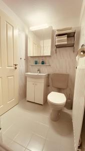 ein weißes Bad mit einem WC und einem Waschbecken in der Unterkunft Moin.Moin 2 in Grömitz