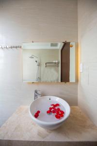 a bathroom with a sink with red flowers in it at Central Hue homestay in Hue