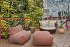 eine Terrasse mit zwei Stühlen und einem Hocker auf einem Deck in der Unterkunft De Cardo Boutique in Jerusalem