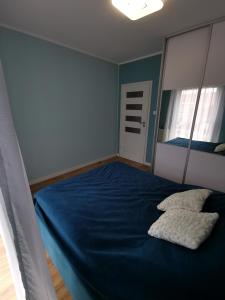 ein Schlafzimmer mit einem blauen Bett mit zwei Kissen in der Unterkunft Apartamemt Królowej Jadwigi in Giżycko
