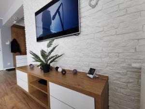 einen TV an einer Ziegelwand mit einem Holztisch in der Unterkunft Apartamemt Królowej Jadwigi in Giżycko