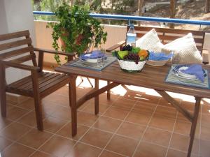 uma mesa de madeira com uma tigela de fruta e uma cadeira em Vivienda en residencial con piscina em Garrucha