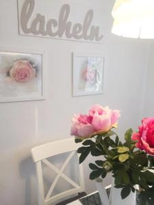 um quarto branco com uma cadeira branca e rosas rosas em Ferienwohnungen in der Uckermark em Schönermark