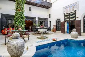 a house with a swimming pool and a patio with a fountain at Riad Makila in Marrakech