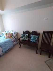 a room with a bed and a bench and a chair at Affordable and Comfortable Serin East Tagaytay Condominun in Tagaytay