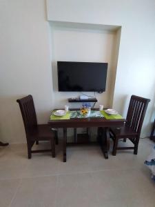 a dining room table with two chairs and a television at Affordable and Comfortable Serin East Tagaytay Condominun in Tagaytay