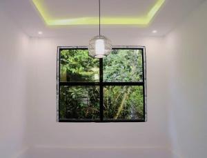 uma janela num quarto branco com uma luz pendente em Purple Orchid Bed and Breakfast em Tagaytay