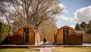2 structures en bois dans une cour avec un arbre dans l'établissement Highland & Transylvania Glamping Pods, à Roybridge