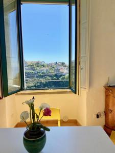 un jarrón con flores en una mesa frente a una ventana en Antica Dimora Amalfi Coast, en Scala