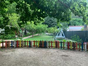 a colorful fence with a park in the background at Adabella Pension in Cıralı