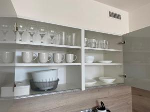 a kitchen with white shelves with glasses and bowls at Apartment David O2 Arena Prague in Prague