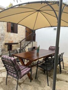 a wooden table and chairs under an umbrella at DROUSHIA CORNER HOUSE in Drousha