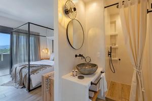 a bathroom with a sink and a bedroom with a bed at Evais Boutique Houses & Luxury Suites in Karistos