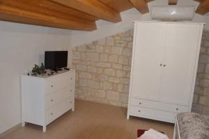 a living room with a tv on a white dresser at Il Carrubo Holiday House in Scicli