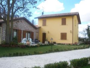 una gran casa amarilla con entrada de grava en Agriturismo Lo Sgorzolo, en Pergola