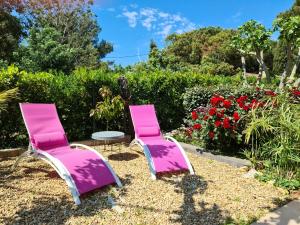 2 chaises roses et une table dans un jardin dans l'établissement Le Hameau de la Nicolinière, à Bormes-les-Mimosas