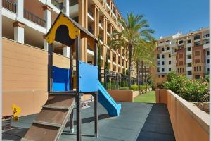 plac zabaw z niebieską zjeżdżalnią przed budynkiem w obiekcie Penthouse with sea views in Marbella w Marbelli