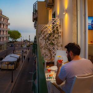 a man sitting at a table on a balcony with a drink at La Serenata Luxury in Maiori